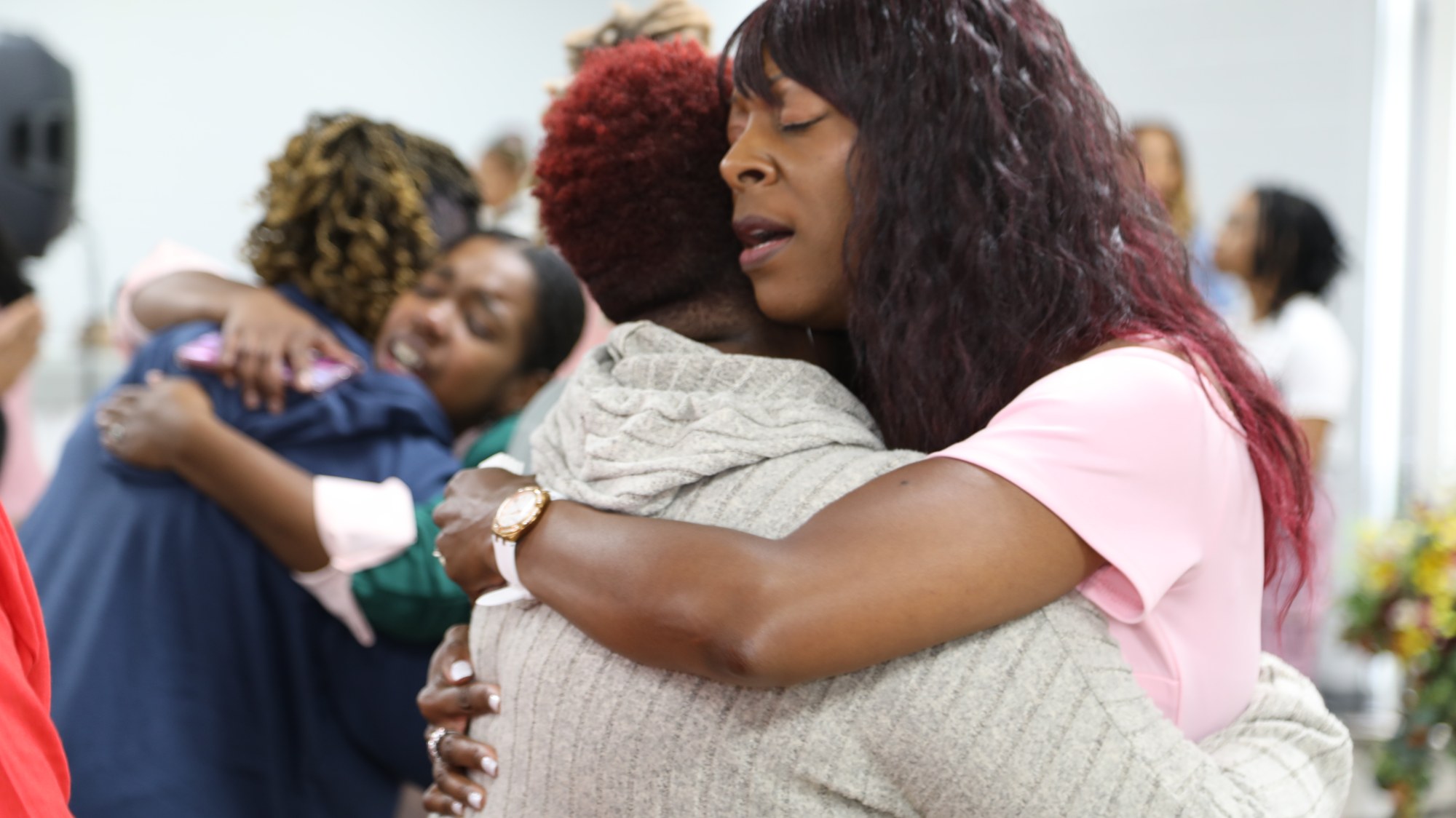 Women embracing in prayer at Purposed Women